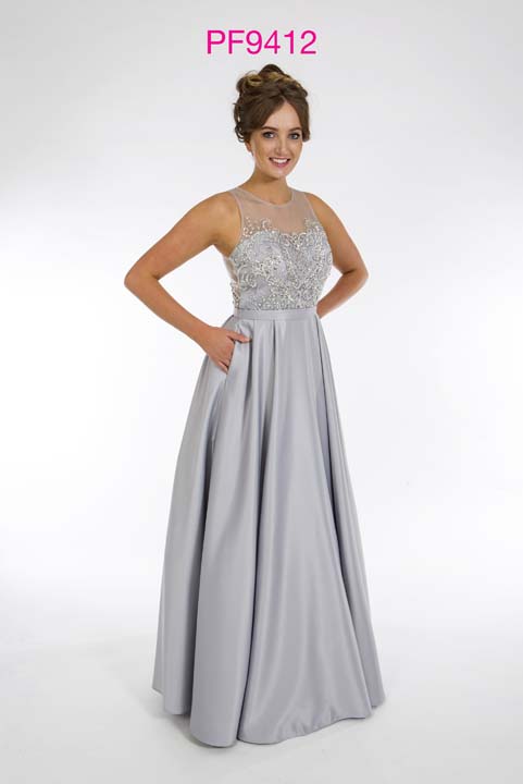 Prom girl wearing silver satin princess gown with beaded illusion bodice and full skirt with pockets.