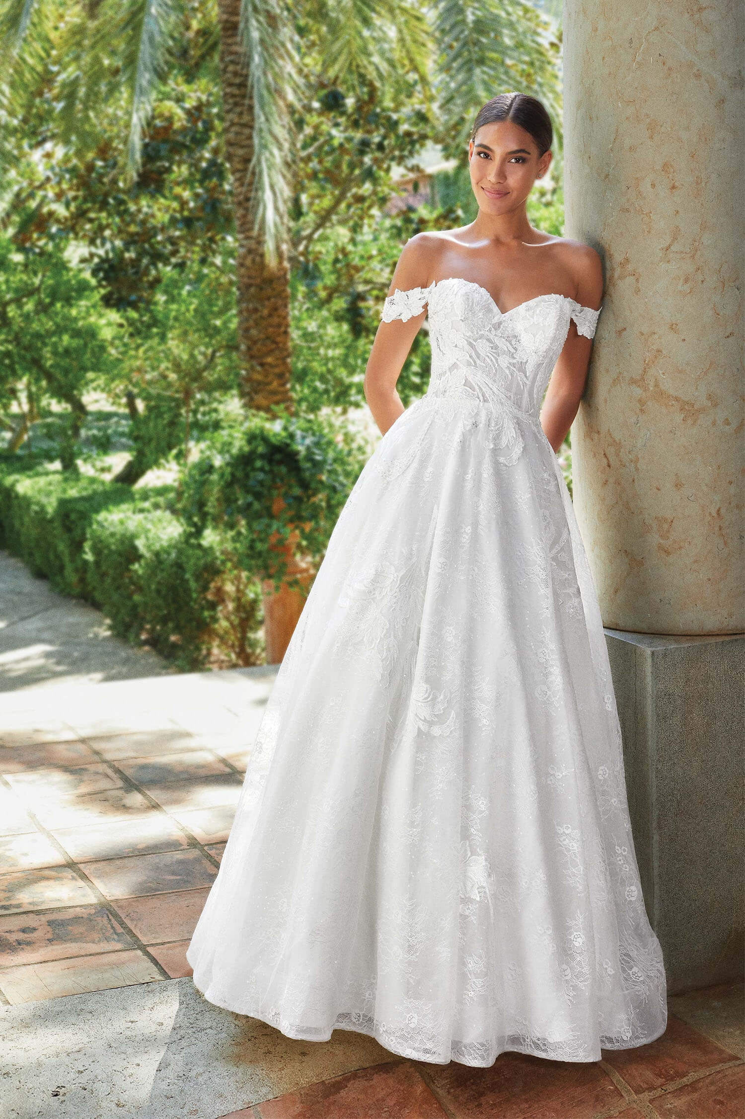 A bride wearing a princess style gown with sweetheart neckline and lace arm swags.