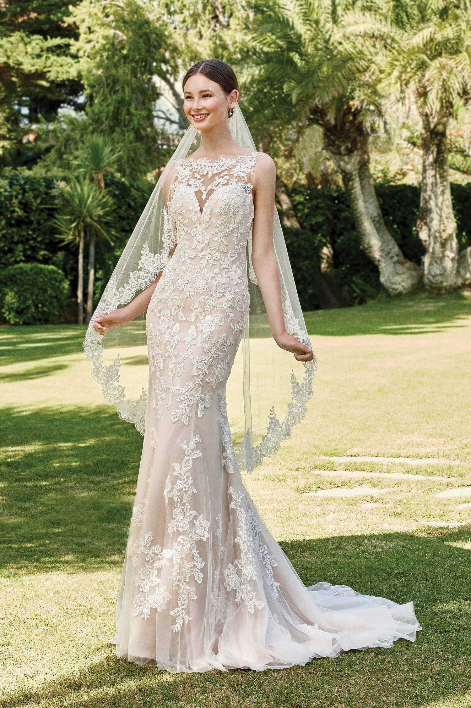 Bride wearing a trumpet style gown with illusion neckline and all over lace appliques, finished with a matchinh hip length veil.