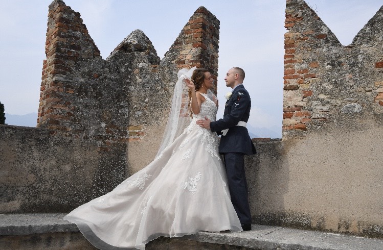 Bride and groom posing near some battlements in Lake Garda