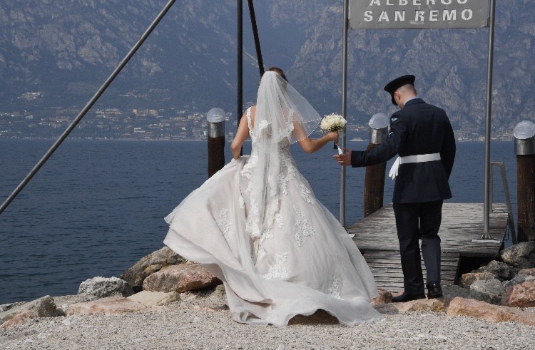 Bride and groom walking on a jetty over Lake Garda.