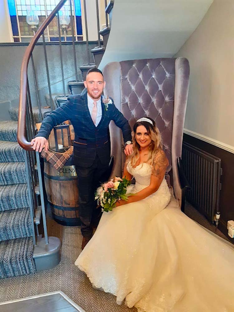 Bride and groom posing for a picture in the hallway at their hotel