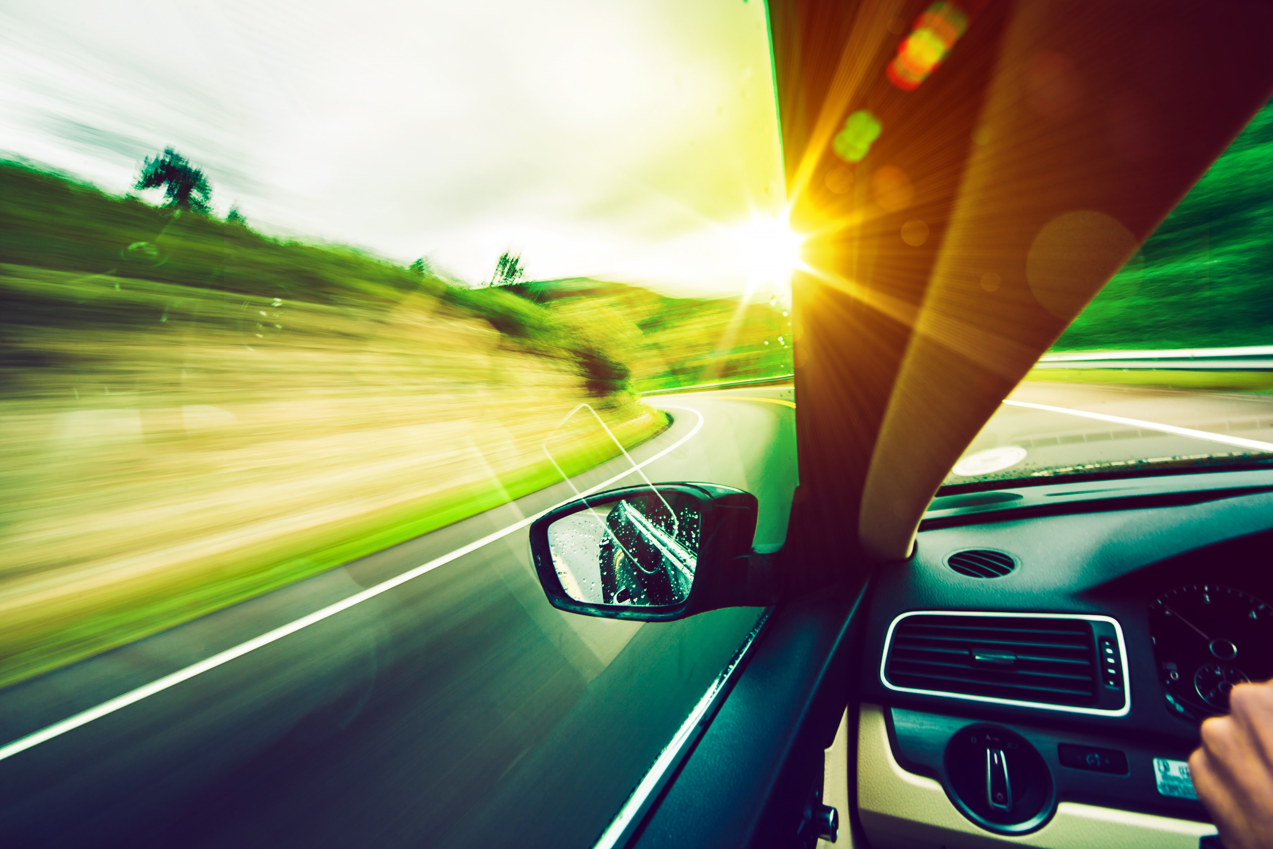 Car driving down road on a sunny day