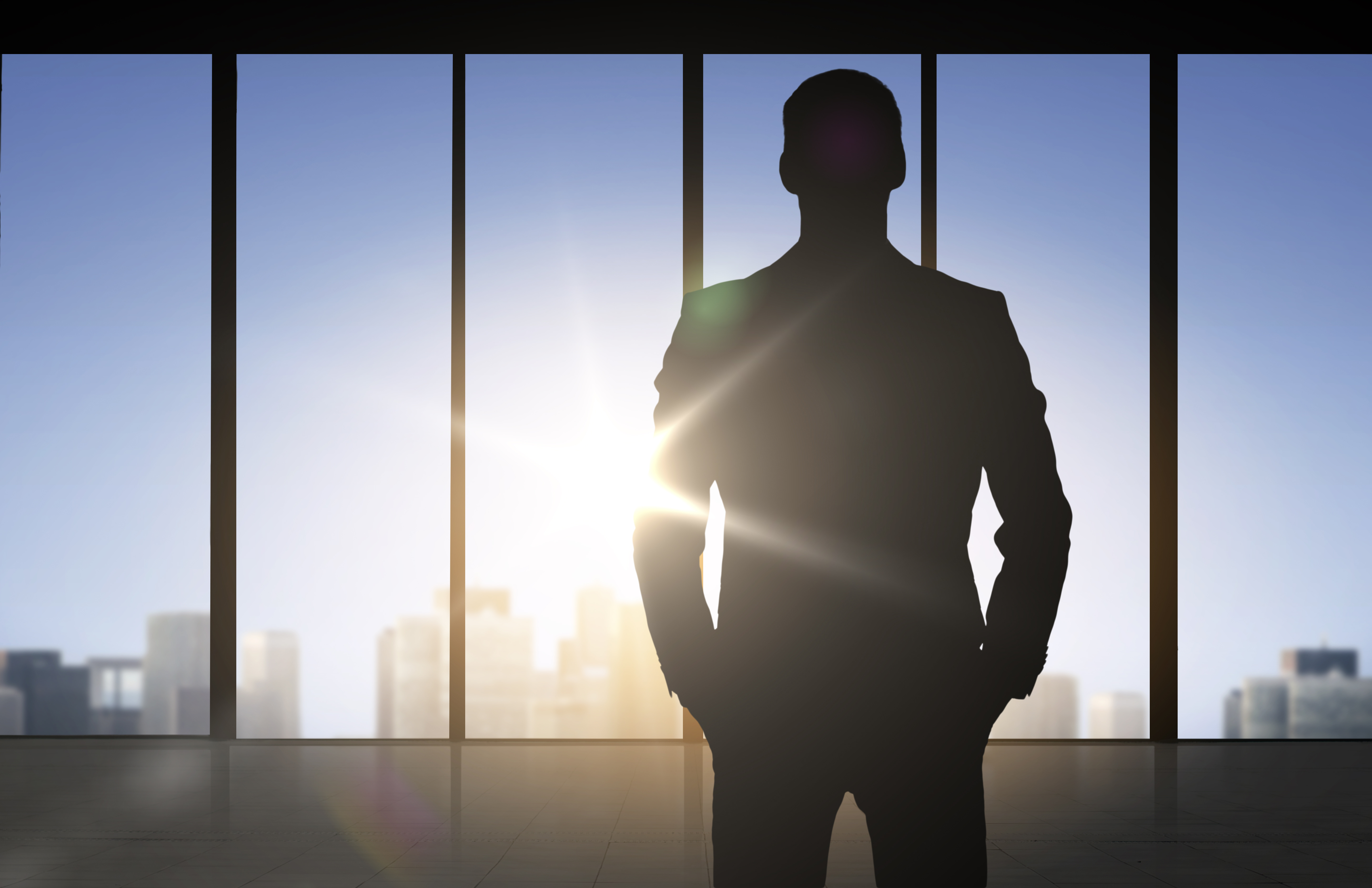 Man standing in office building looking out window.