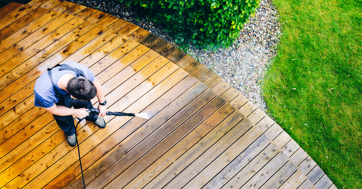 man pressure washing deck