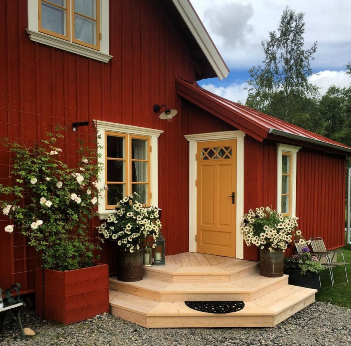 An exterior shot of a sophisticated country house painted vibrant red with mustard trim