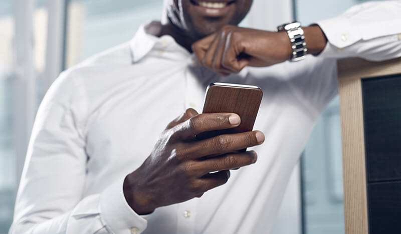 Image of a man holding a mobile phone, which is focused in the foreground - OttoLearn Personalized Learning