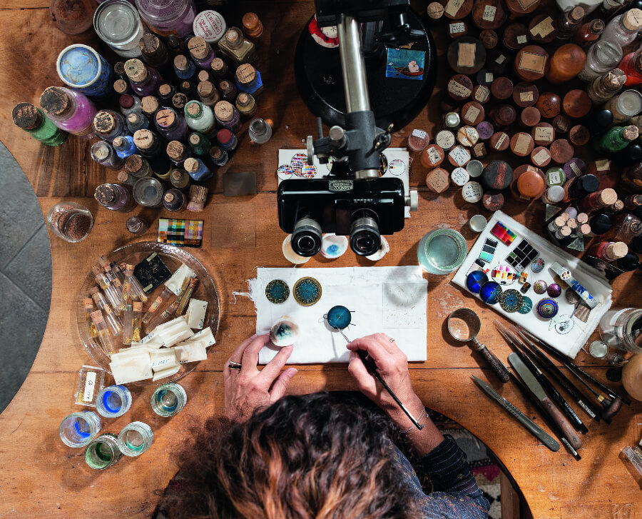 Anita Porchet is meticulously applying thin layers of enamel to reach the desired graded hues of blue on one of the dials of the trilogy