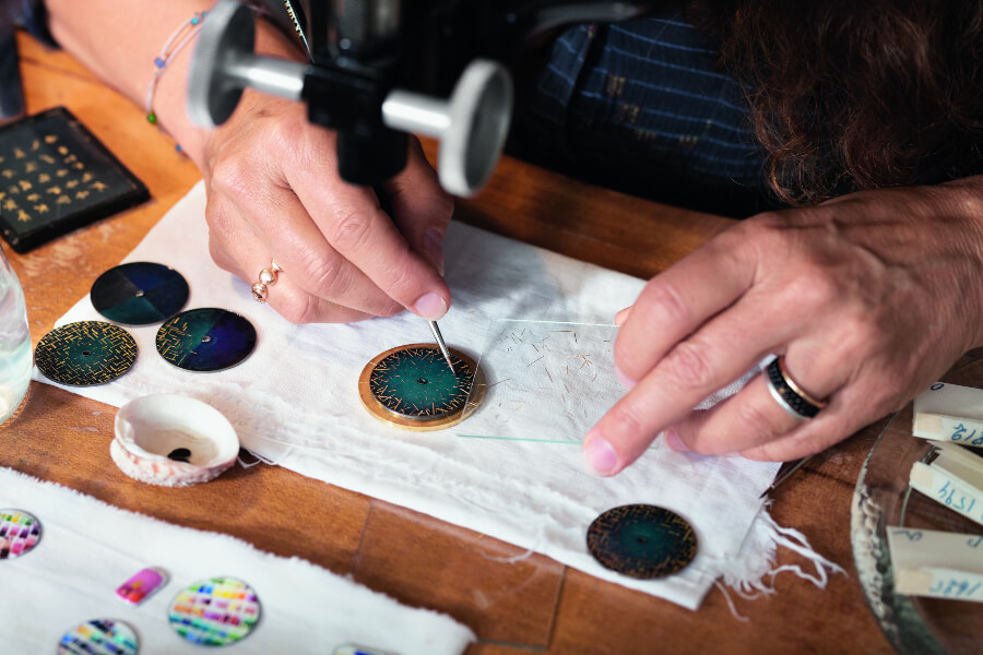 Anita Porchet is carefully positionning by hand each unique gold spangle on the blue enamelled dial