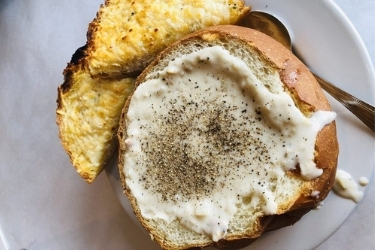 Clam Chowder in a bread bowl with two pieces of bread