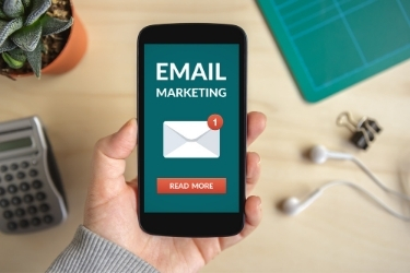 Hand holding a phone with a new Email Marketing Campaign