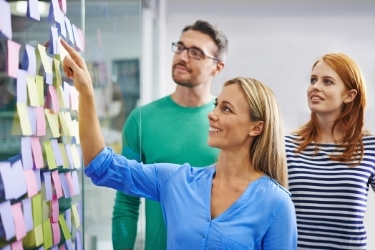 Woman pointing at a post it pasted in a Bulletin Board
