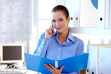 Woman talking through the phone with an open folder