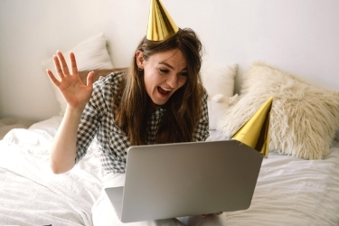 Woman with party hat moving her hands in front of her laptop