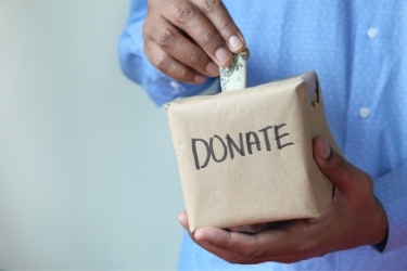 Hands putting money inside a Donation Box