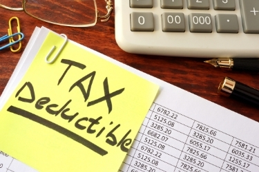 Stack of files with a post it that says "Tax Deductible"