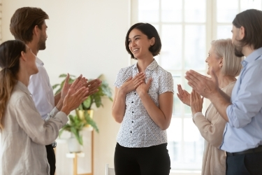 People at work applauding a woman standing in the middle