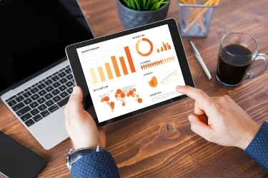Hands holding a tablet with a CRM software dashboard