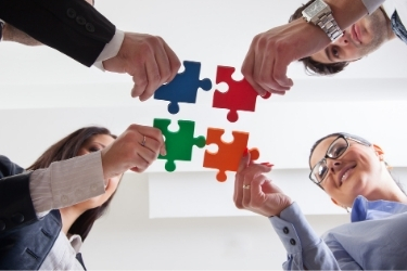 Company workers connecting a few puzzle pieces together