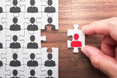 Hand adding a missing piece of puzzle with a red person icon in it.