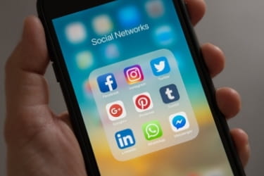 Hand holding a mobile phone with social media apps