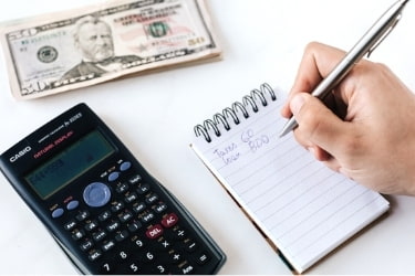 Someone budgeting with a calculator and a notepad