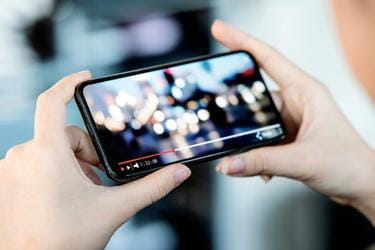 Hands holding a mobile playing a video