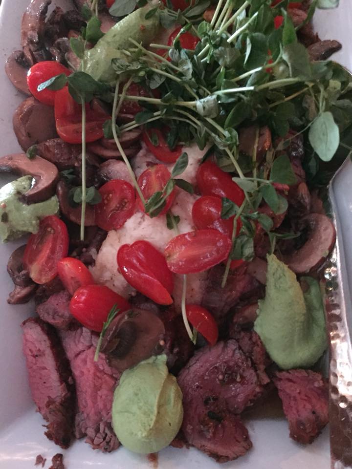 smoked bistro steak with creamed horseradish parmesan potatoes, pea pesto, pea shoots, tomatoes, and a mushroom vinaigrette