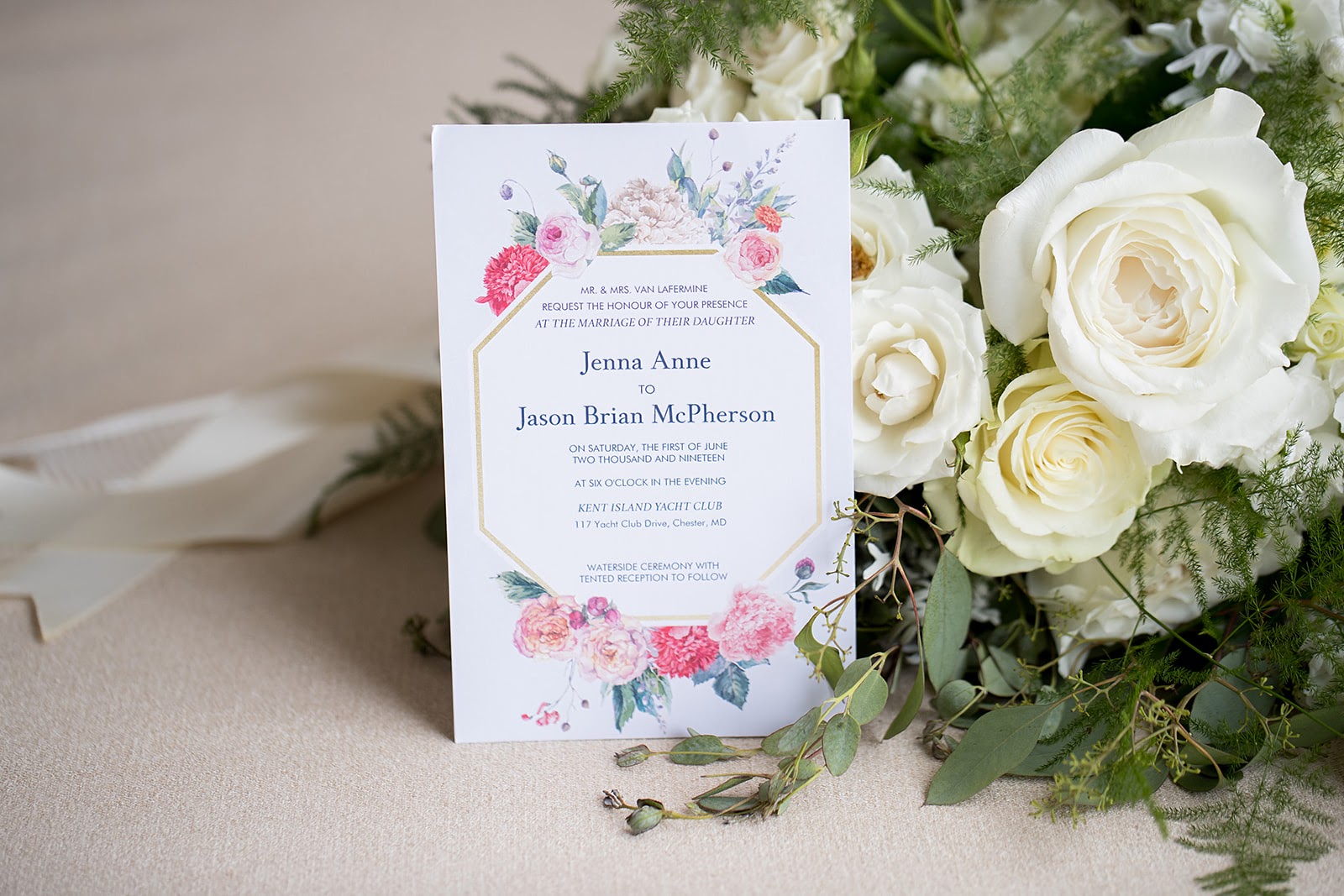 floral wedding invitation beside a bouquet of white roses