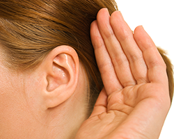 Woman with her hand cupped behind her ear to improve her hearing