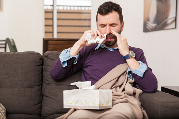 congested man using a nasal spray for his stuffy nose