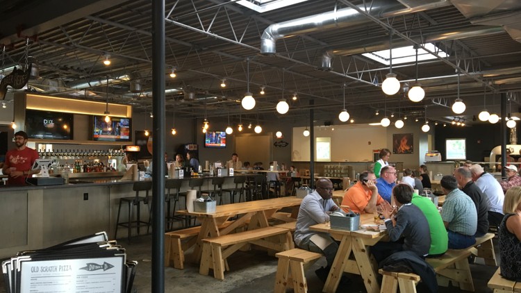 people dining on wooden benches and tables inside of Old Scratch