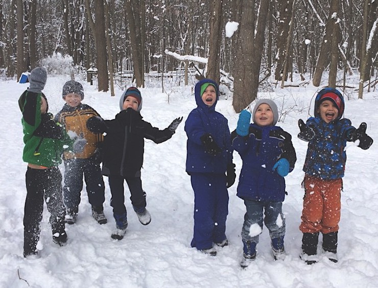 group of kids smiling & throwing snow in the air