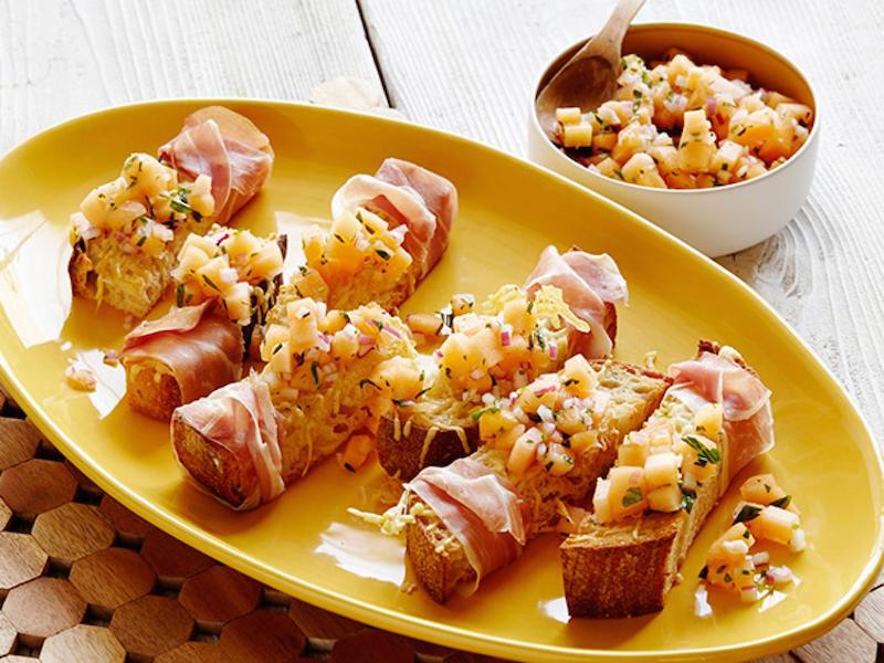 Prosciutto-Wrapped Crostini with Melon Salsa Crudo on a yellow plate