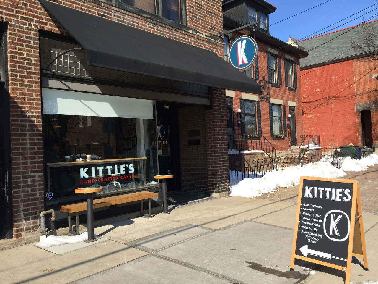 front of Kittie's Cakes building with wooden bench outside