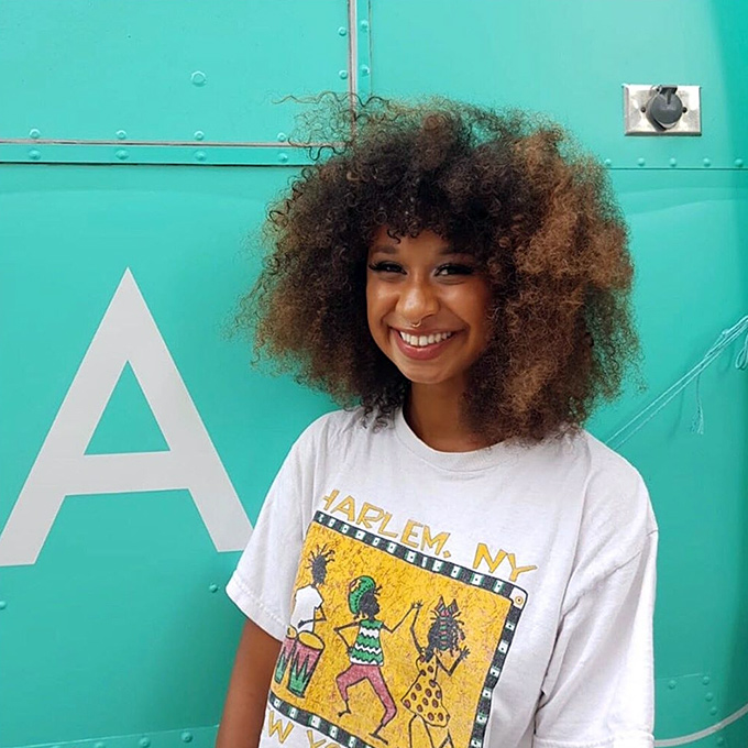 A happy customer with her curly hair styled at the Antidote Hair Lab Bus