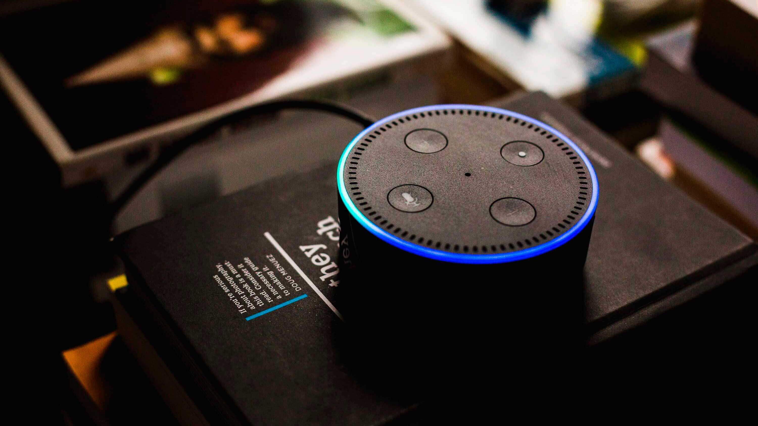 Como a IoT está criando um mundo hiperconectado? - Alexa, IoT da Amazon, em mesa de escritório cheia de livros.