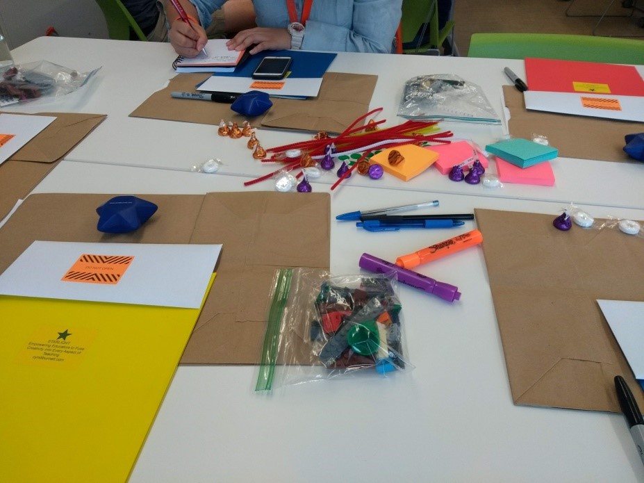 Mesa com cartolinas, peças de lego, canetas coloridas e post-its