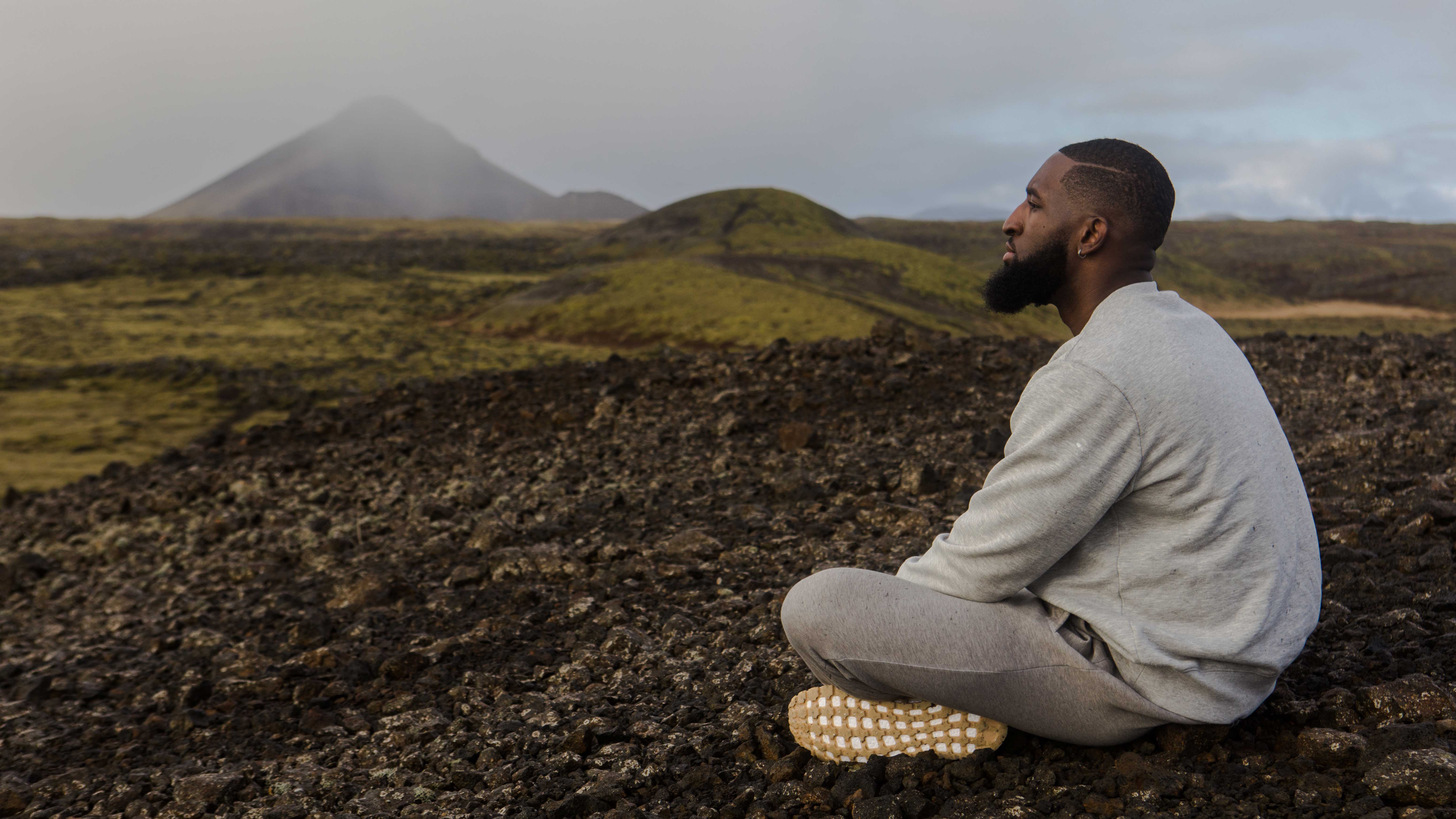 Homem meditando com montanhas atrás.