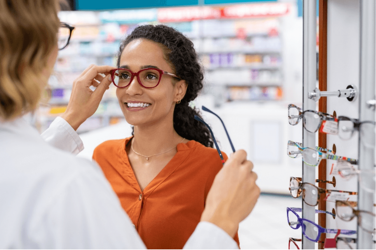 Optometrist assisting a woman with trying on eyeglasses