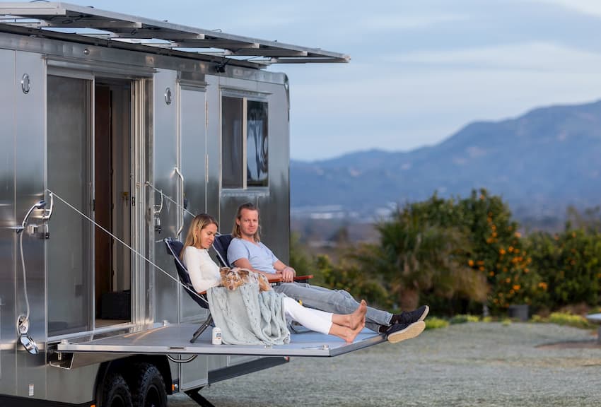People sitting on the deck of a luxury travel trailer