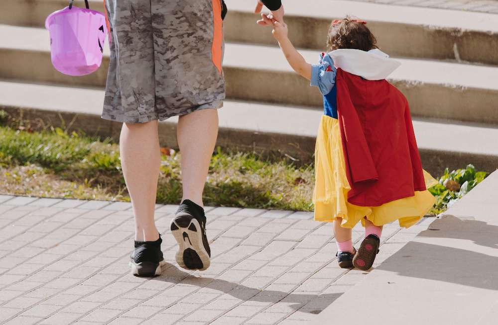 Photo of a young girl dressed as Sleeping beauty holding hands with a parent out of frame