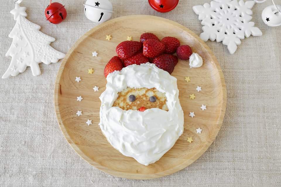 Photo of a pancake with Santa made of strawberries and whip cream on it