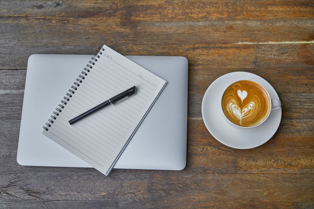 MacBook, cuaderno y café.