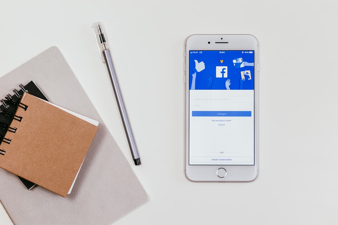 Celular con Facebook, cuaderno y lapicero.