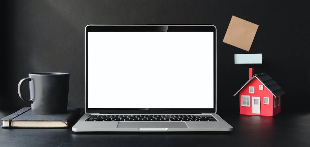 Laptop, una taza de café, una casa roja, marketing inobiliario