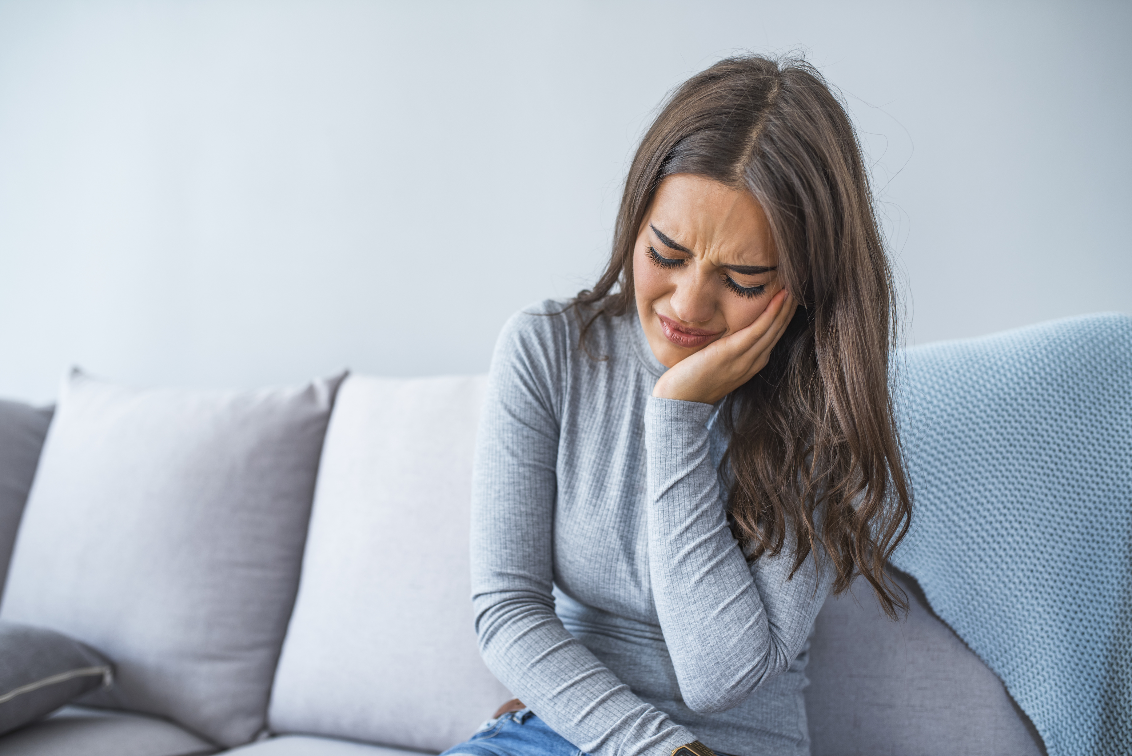 Woman sitting on a chair holding her jaw in pain