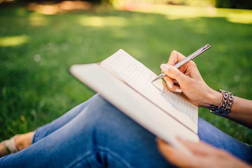 A person writing on a pad on their knee's