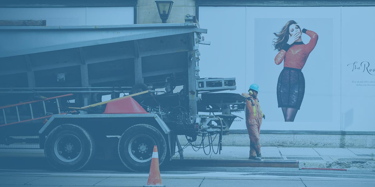 A workman at the back of a truck in front of a Billboard