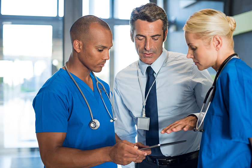 3 clinicians discussing in-house staffing over an iPad